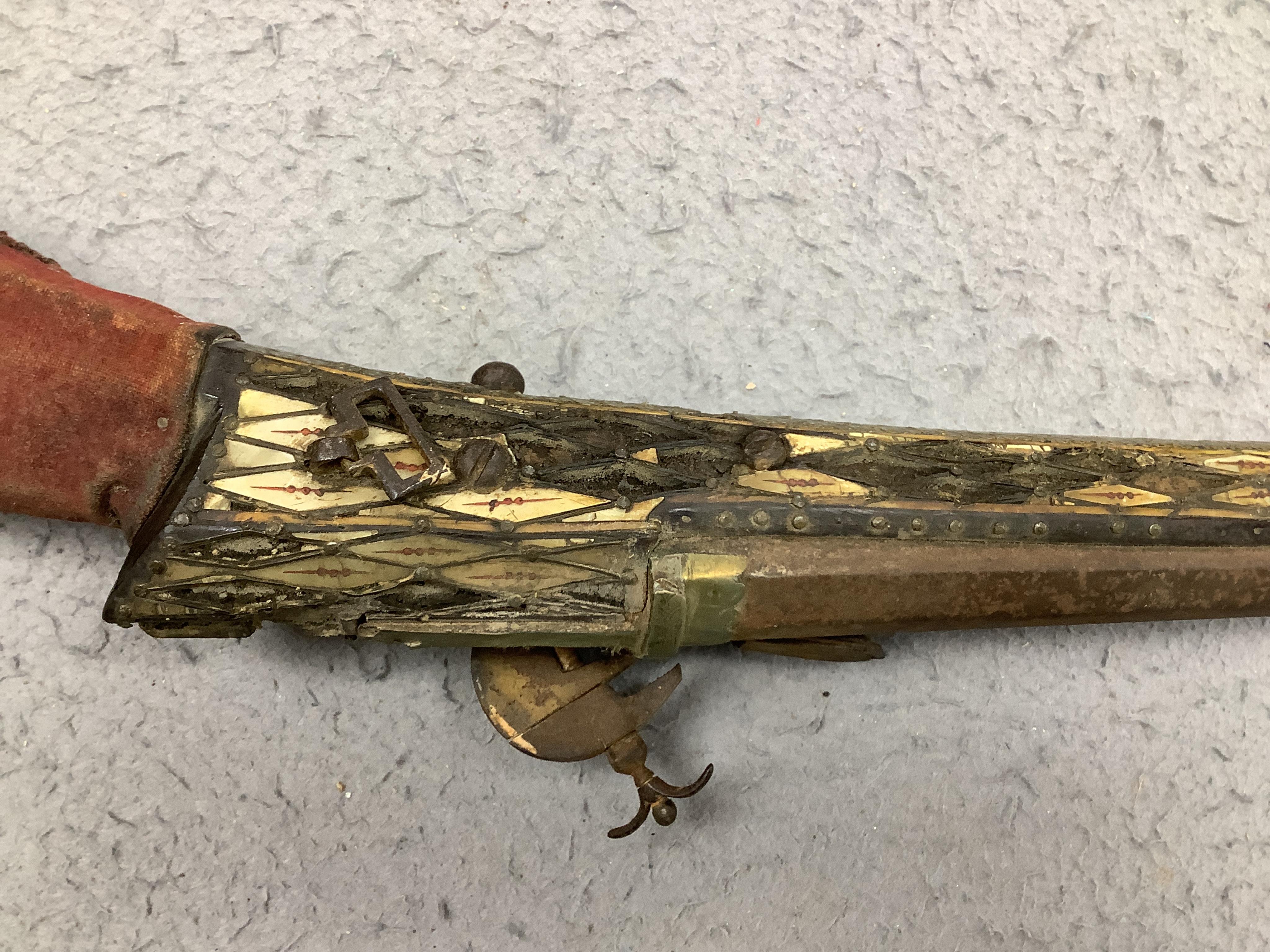 An Indian axe bhuj, with broad curved blade, iron haft with elephant head top, all covered over with silver gilt foil engraved with flower heads, the pommel unscrews to reveal a stiletto, with its copper mounted sheath,